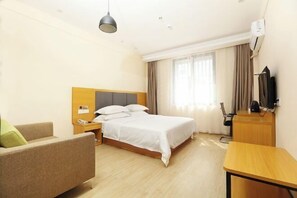 A hotel room with a bed, a desk, a chair, and a television.