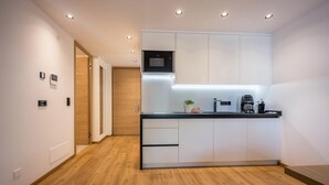 Een moderne keuken met witte kastjes, een ingebouwde magnetron en een koffiezetapparaat.