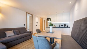Een moderne woonkamer met een bank, een eettafel en een keuken in de achtergrond.