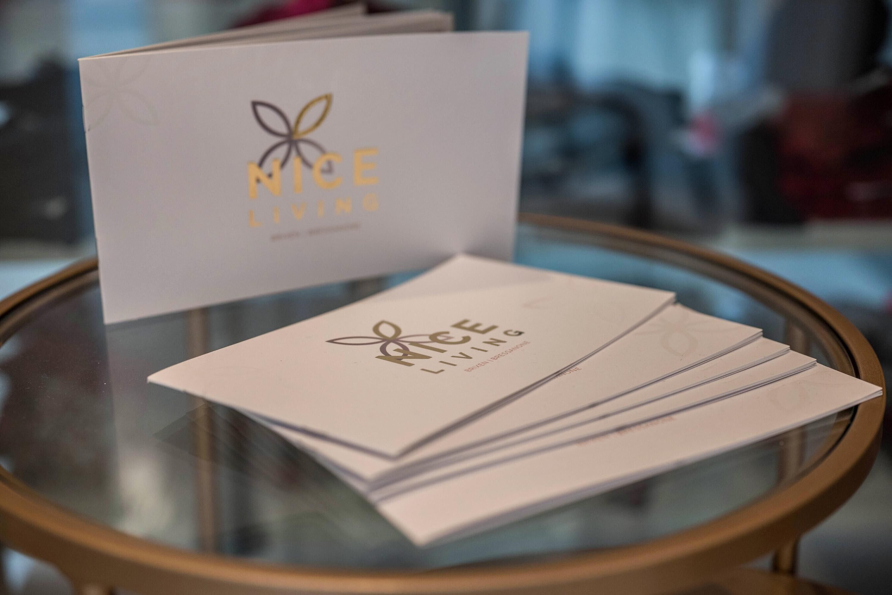 A glass table with a stack of business cards and a card with 'NICE LIVING' branding.
