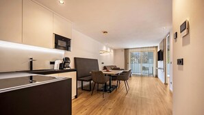 A modern kitchen with a dining area, wooden flooring, and a large window. - Modern Apartment "Nice 4" with Balcony in the Center of Bressanone/Brixen (Brixen)