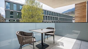 A balcony with a table and chairs, a glass wall, and a view of a building and tree. - Modern Apartment "Nice 4" with Balcony in the Center of Bressanone/Brixen (Brixen)