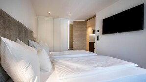 Ein modernes Hotelzimmer mit einem großen Bett, einem flachbildfernseher an der Wand und einem Kleiderschrank.