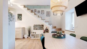 A modern interior with a staircase, dining area, and a flat-screen TV.