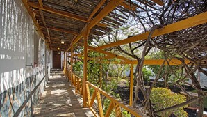 A covered walkway with a wooden ceiling and yellow railings, leading to a building with a stone facade. - Finca Fani 4 with Mountain Views, Shared Pool, Wi-Fi, Terrace & Garden (Agüimes)