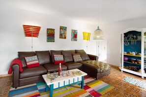 A living room with a brown sofa, colorful striped rug, and wall art.