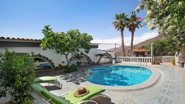 A swimming pool with lounge chairs and a palm tree. - Finca Fani 4 with Mountain Views, Shared Pool, Wi-Fi, Terrace & Garden (Agüimes)
