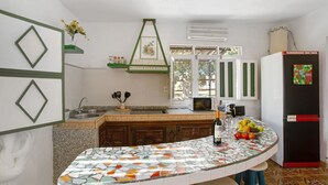 A kitchen with a tiled island, a refrigerator, and a microwave. - Finca Fani 4 with Mountain Views, Shared Pool, Wi-Fi, Terrace & Garden (Agüimes)