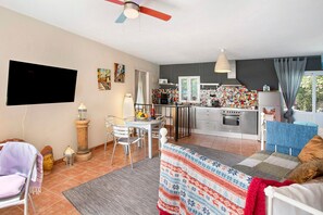 A modern living room with a TV, dining area, kitchen, and a balcony with a view.
