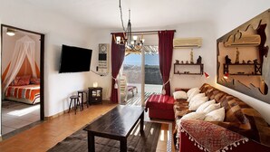 Un salon avec un canapé, une table, un téléviseur et un balcon offrant une vue agréable.
