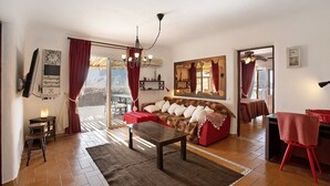 Un salon comprenant un canapé, une table basse, un téléviseur et un coin repas avec une table et des chaises.