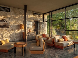 Un interior moderno con paredes de piedra, ventanas amplias y muebles contemporáneos.