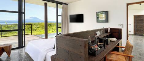 Habitación de hotel moderna con una cama grande, un escritorio de madera, una silla, un televisor de pantalla plana y vistas a la montaña.