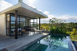 Una casa moderna con piscina, terraza de madera y zona de estar al aire libre.