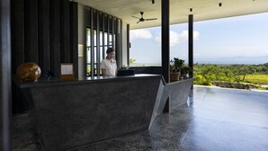 A modern reception area with a receptionist, a large decorative vase, and a view of the landscape.