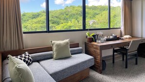 A modern room with a large window, a sofa, a desk, and a chair.