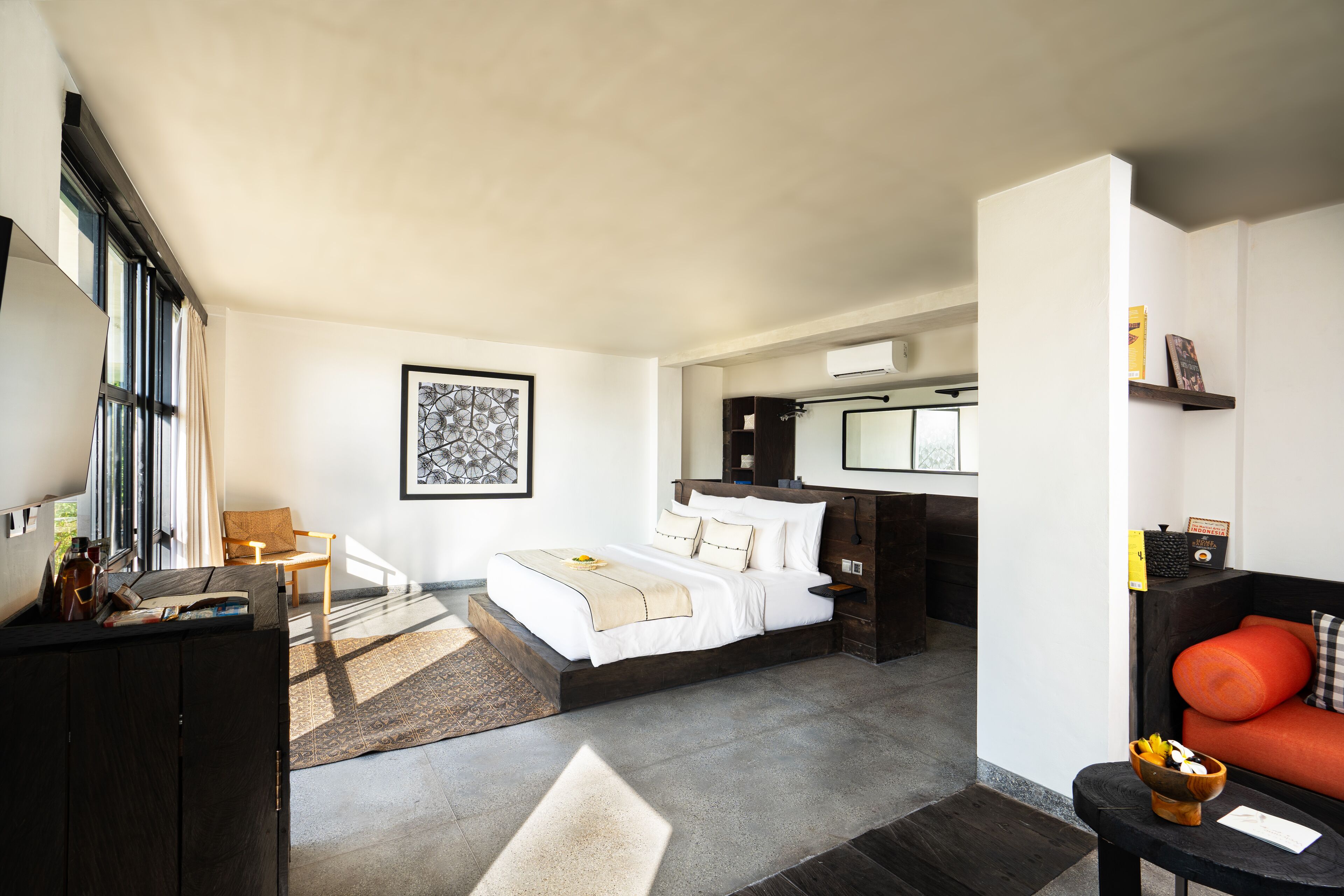 A modern hotel room with a large bed, a desk, a chair, a sofa, and a small table.