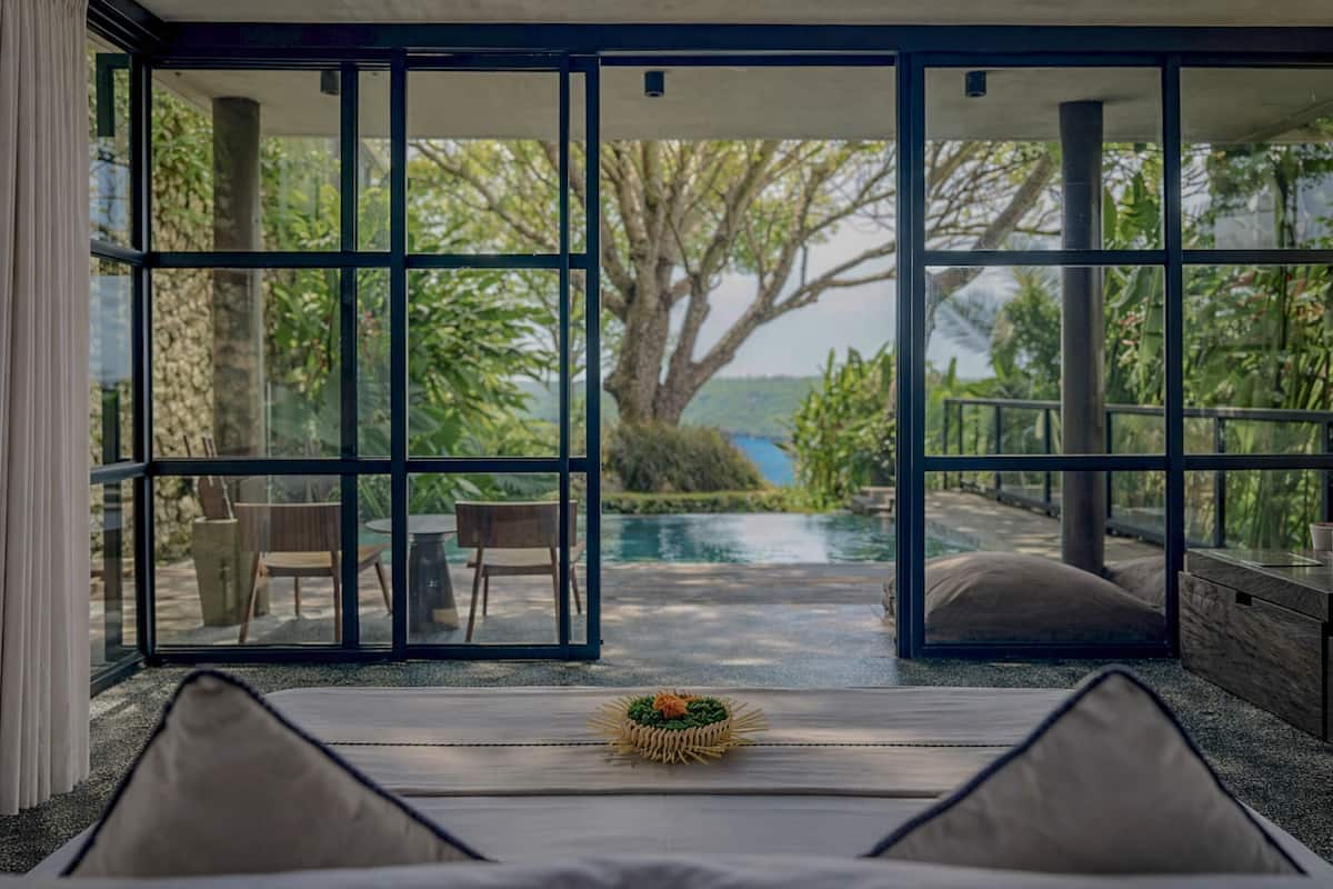 A room with a large sliding glass door leading to an outdoor area with a pool and greenery.