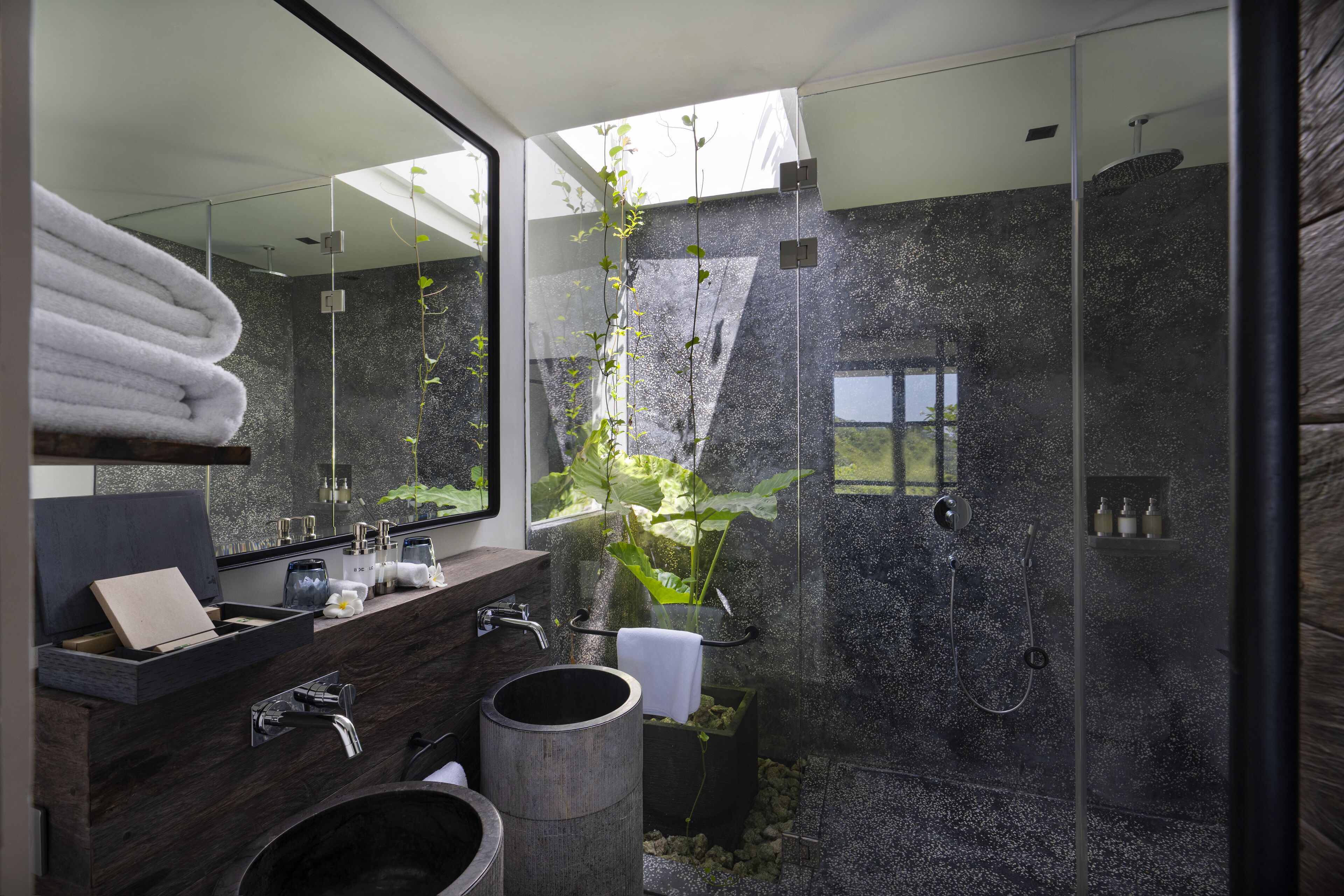 A modern bathroom with a glass shower enclosure, a wooden vanity, and a large mirror.