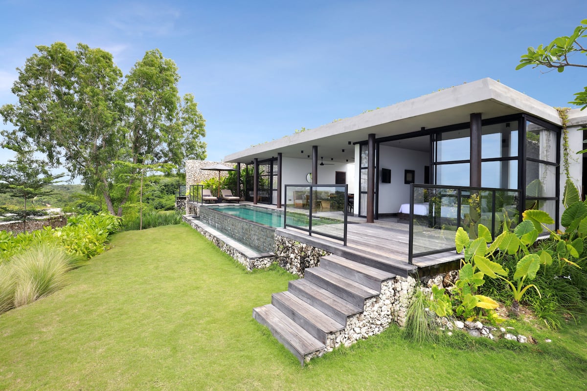 A modern house with a pool, large windows, and a stone pathway.