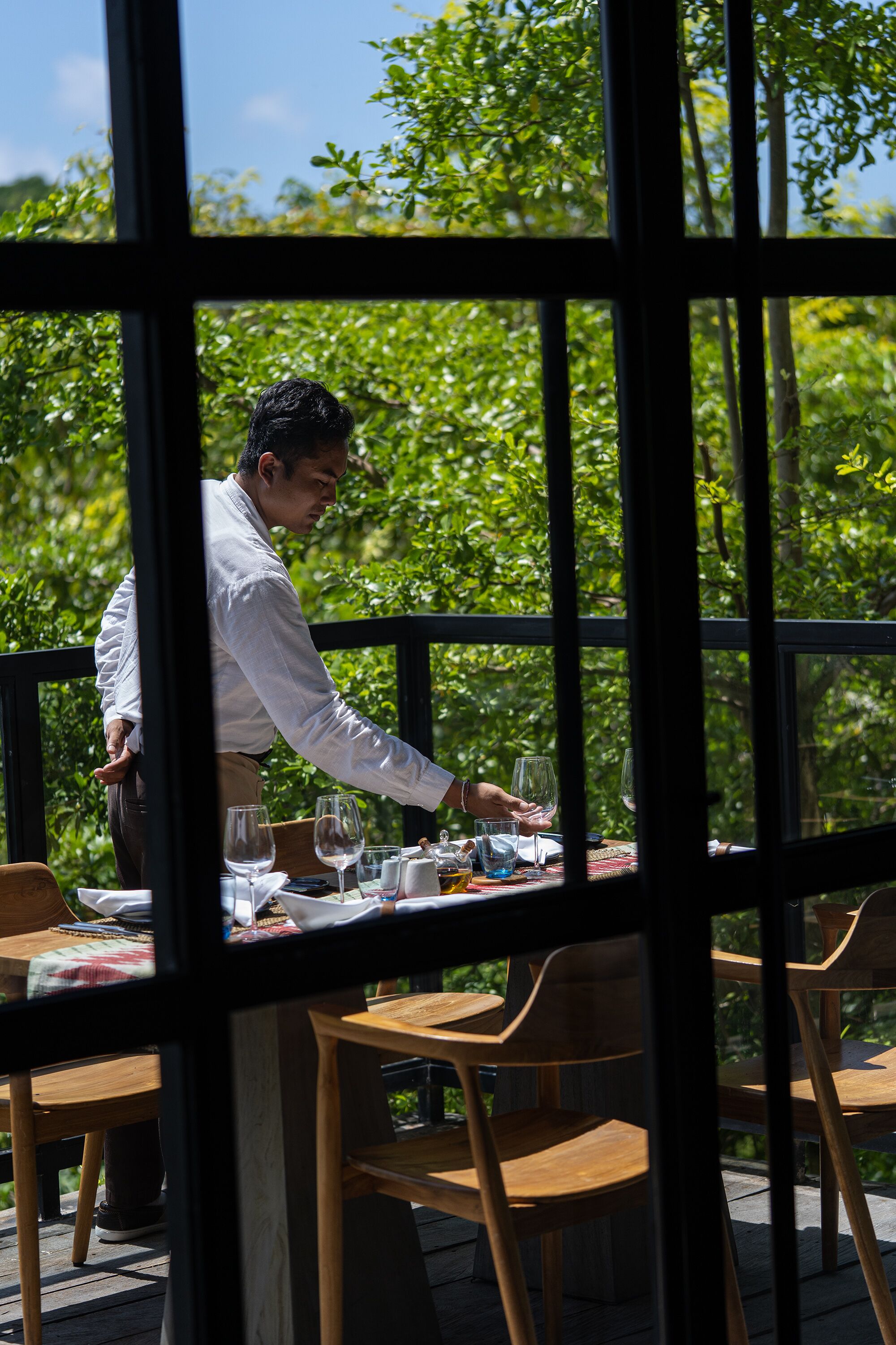A restaurant with a view of lush greenery through large windows.
