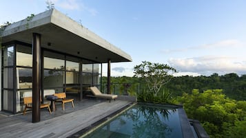 A modern outdoor pool area with a wooden deck, lounge chairs, and a glass-enclosed structure.