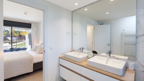 Un baño moderno con dos lavamanos, un espejo grande y una cama con vista al exterior.