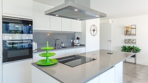 Una cocina moderna con horno empotrado, campana extractora de acero inoxidable y una isla central con fregadero.