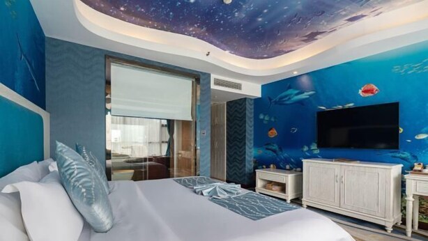 Un dormitorio con cama, televisión y un mural de peces en la pared.
