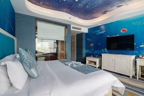 A bedroom with a bed, a TV, and a wall mural of fish. - Yuhe Hotel (Leshan)