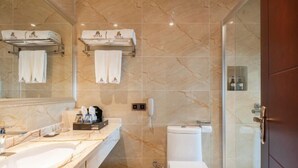 Un baño moderno con tocador de mármol, inodoro y cabina de ducha de vidrio.