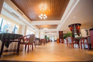 A spacious hotel lobby with a high ceiling, wooden paneling, and a central seating area with chairs and tables. - Yuhe Hotel (Leshan)