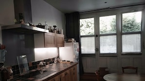 A kitchen with wooden cabinets, a tiled backsplash, and a dining area with a table and chairs. - Family home in the country (groslee saint benoit)