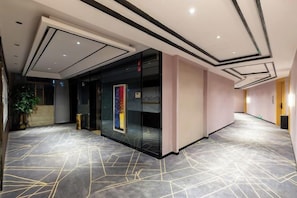 A spacious hallway with a geometric patterned floor, a glass wall with a colorful artwork, and a modern ceiling design. - ShangPing xifeng Hotel (Xinfeng)