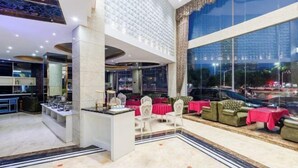 Un moderno vestíbulo de hotel con una zona de bar central, arreglos de asientos y ventanas amplias con vistas a la ciudad.