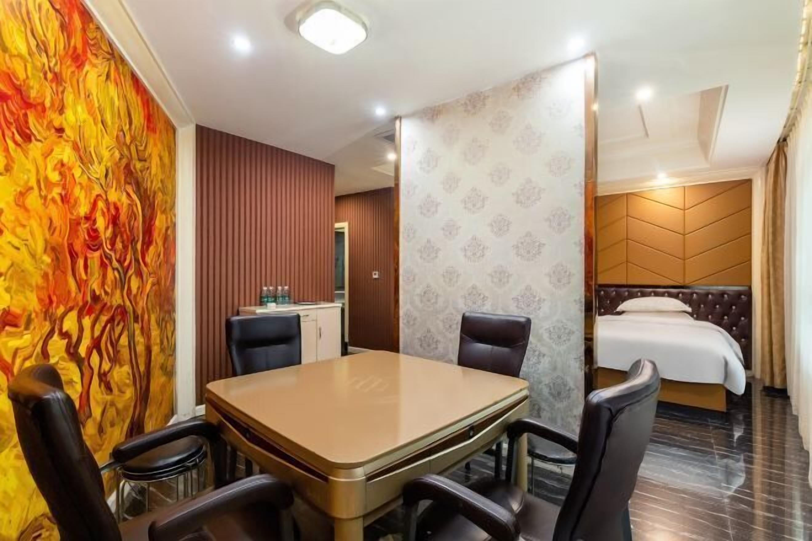 A hotel room with a dining area, a bed with a headboard, and a bathroom visible through a door.