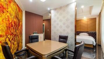 A hotel room with a dining area, a bed with a headboard, and a bathroom visible through a door.