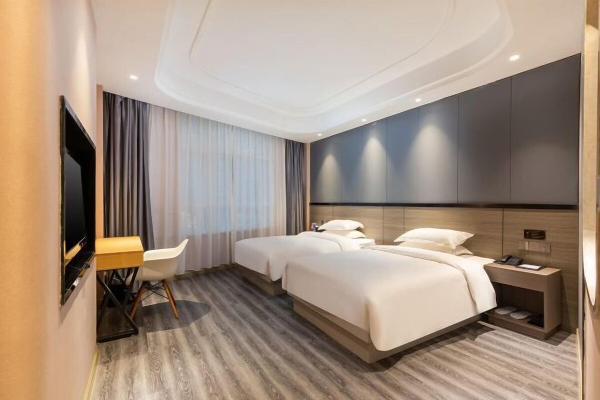 Ein modernes Hotelzimmer mit einem großen Bett, einem Schreibtisch und einem Fernseher.