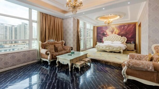 Una habitación lujosa con una cama grande, una zona de estar con sofá y sillón, una mesa de centro y vistas a rascacielos.