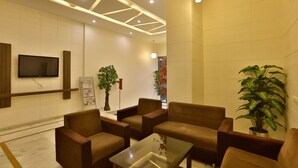 Un hall moderno con sofás, una mesa de centro, televisión y plantas decorativas.