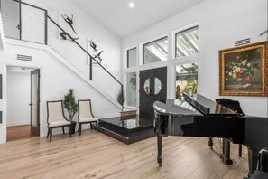 Experience music and art in this elegant space, featuring a grand piano and artwork, including a beautiful floral painting.