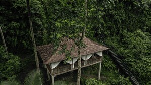 A treehouse with a tiled roof and white curtains, surrounded by dense forest. - Exceptional 9BR Incredible Jungle View, River Access (Ubud)
