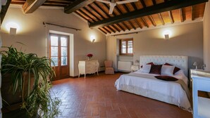 A bedroom with a large bed, a ceiling fan, a potted plant, and a wooden ceiling. - Timeless Tuscan Holiday Stay (Unknown)