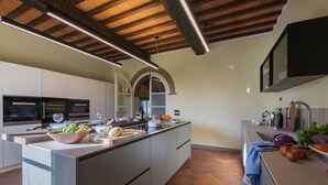 A modern kitchen with a central island, built-in appliances, and a large window. - Timeless Tuscan Holiday Stay (Unknown)