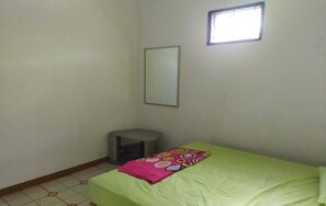 A small, sparsely furnished room with a single bed, a small stool, and a window. - Baciro Homestay46 (Yogyakarta)