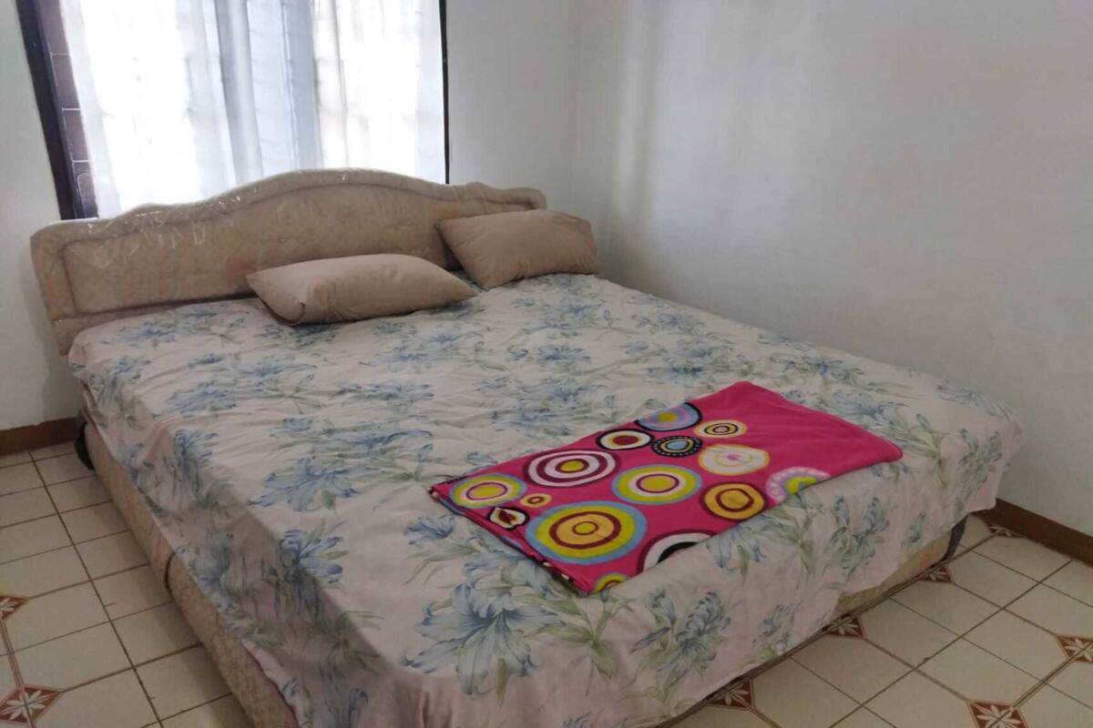 A bedroom with a bed, a window, and a tiled floor.