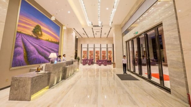 A hotel lobby with a reception desk, a large painting of a lavender field, and a modern interior design. - Lavande Hotel (Dongguan Chang'an Fuhu) (Dongguan)