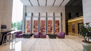 A modern lobby with a reception desk, seating area, and large glass windows. - Lavande Hotel (Dongguan)