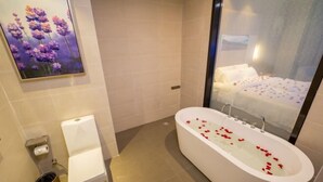 A modern bathroom with a freestanding bathtub, a toilet, and a trash can. - Lavande Hotel (Dongguan)