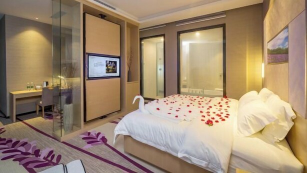 A modern hotel room with a large bed, a desk, and a glass partition. - Lavande Hotel (Dongguan)